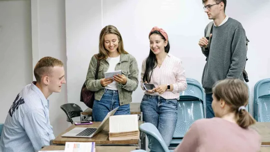 Estudiantes sonríen en un aula con un portátil