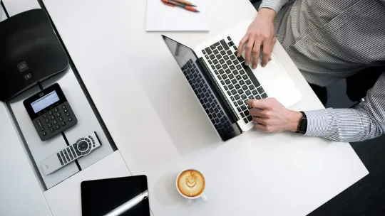 Administrativo comercial en su puesto de trabajo con su portátil.