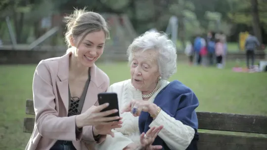 Mujer enseñando tecnologia a una señora mayor