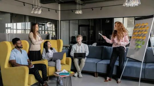Mujer enseña a un grupo de adultos un diagrama en un lienzo.