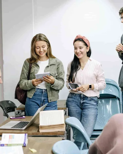 Estudiantes sonríen en un aula con un portátil