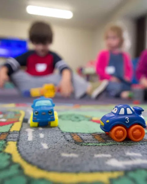 Niños de educación infantil jugando en el suelo con coches de juguetes