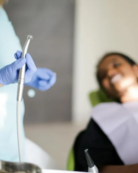 Dentista realiza un curetaje dental en una paciente.