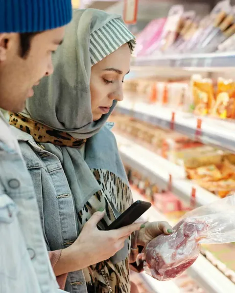 Dos jovenes miran la etiqueta nutricional de un producto en el supermercado.