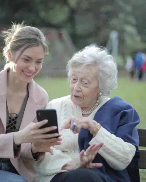 Mujer enseñando tecnologia a una señora mayor