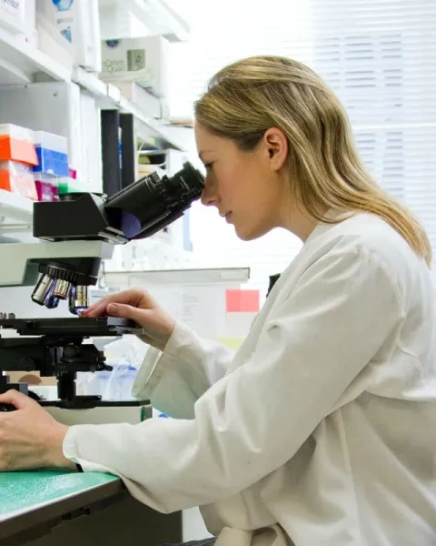 Técnica especialista trabajando con un microscopio en un laboratorio.