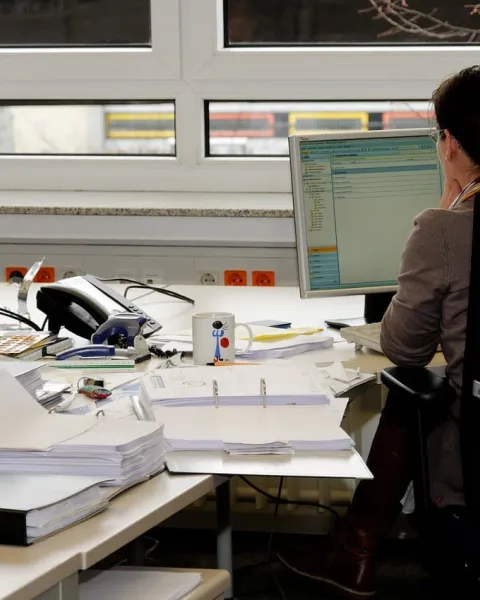 Trabajadora en su puesto de trabajo con muchos documentos.