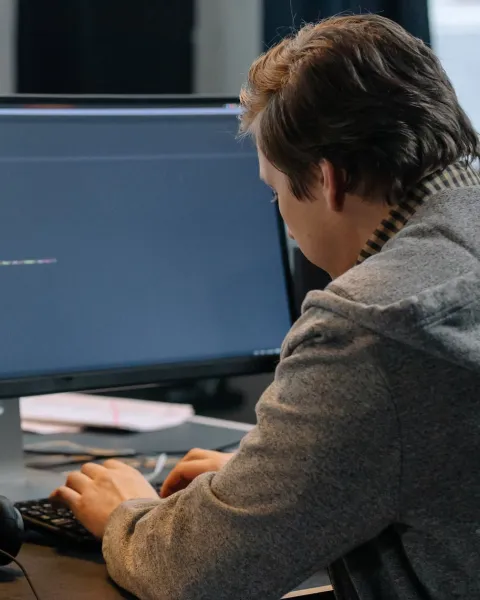 Hombre programando con una pantalla de ordenador