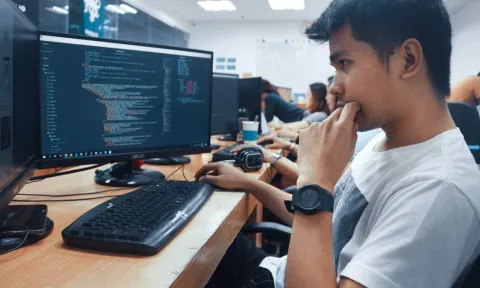 Chico joven delante de una pantalla del ordenador programano